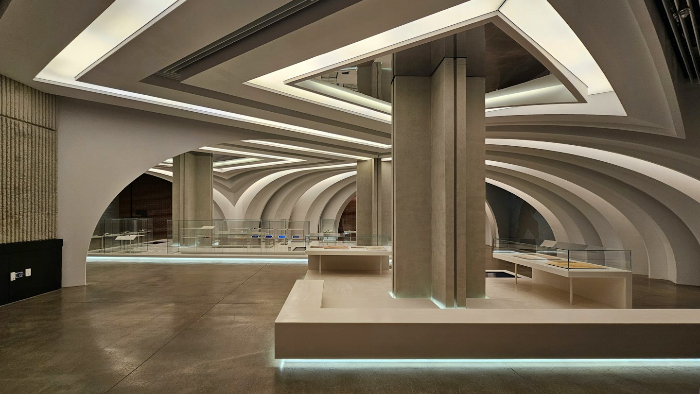 Espacio arquitectónico moderno con paredes arqueadas y columnas de hormigón.