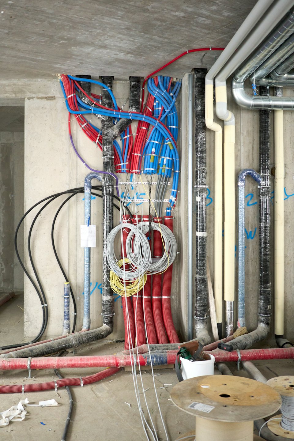 Tuberías y conductos de colores en paredes de hormigón en una obra.