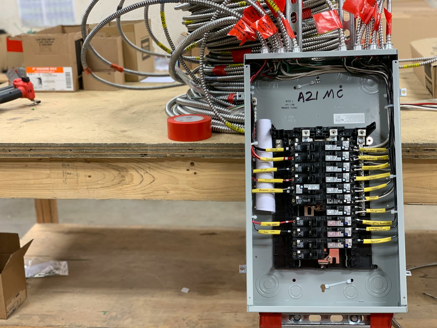 Panel eléctrico siendo cableado en un banco de trabajo con conductos.