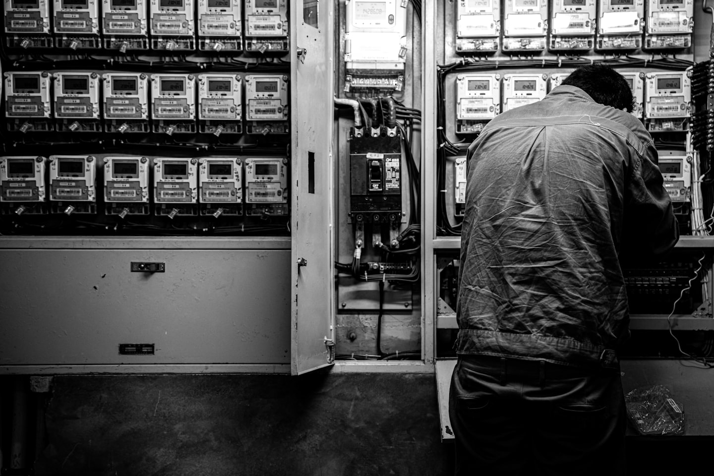 Persona trabajando en un panel eléctrico abierto con cableado complejo.