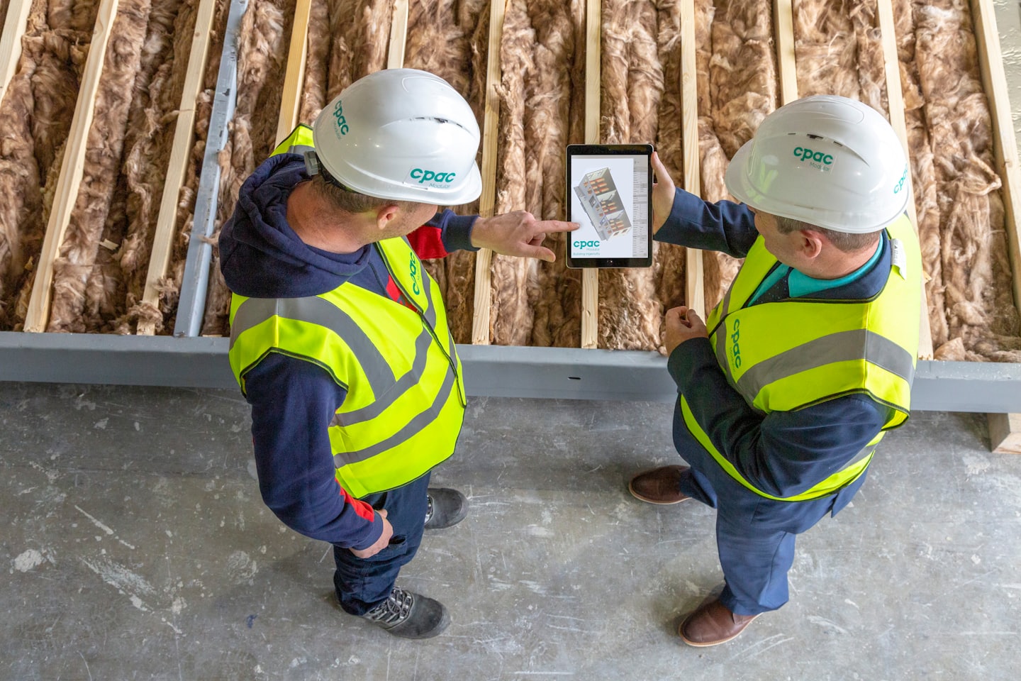 Dos obreros de la construcción comentan una tableta digital en una obra.